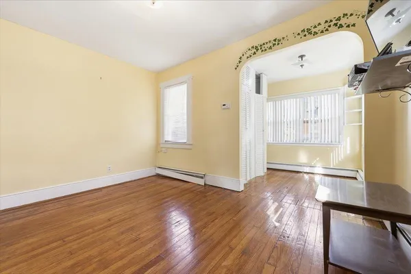 a view of an empty room with wooden floor and a window
