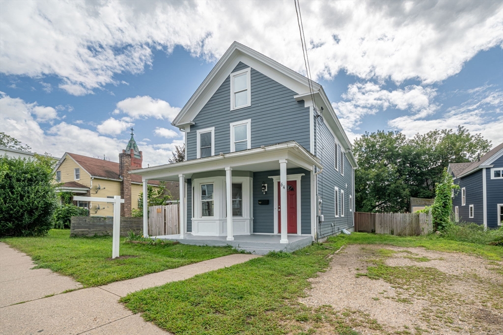 a view of a yard in front of a house with plants and large tree