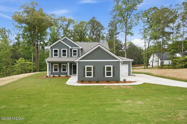 a front view of a house with a garden and trees