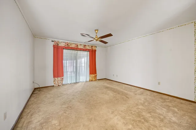 an empty room with a ceiling fan and window
