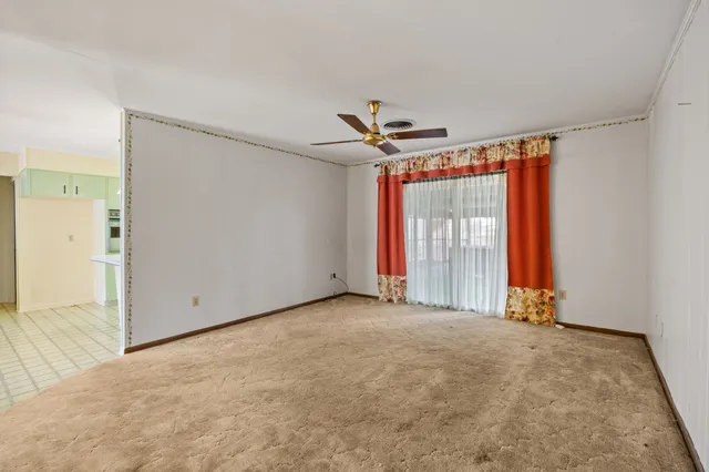an empty room with windows and a ceiling fan