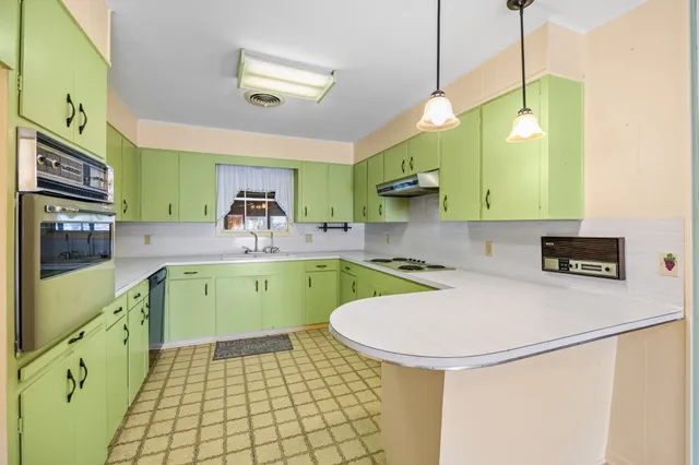 a kitchen with a sink a stove cabinets and wooden floor