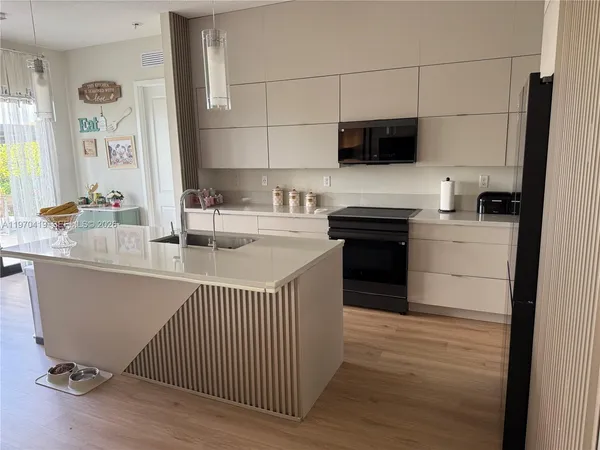a large white kitchen with a large window a sink and stainless steel appliances