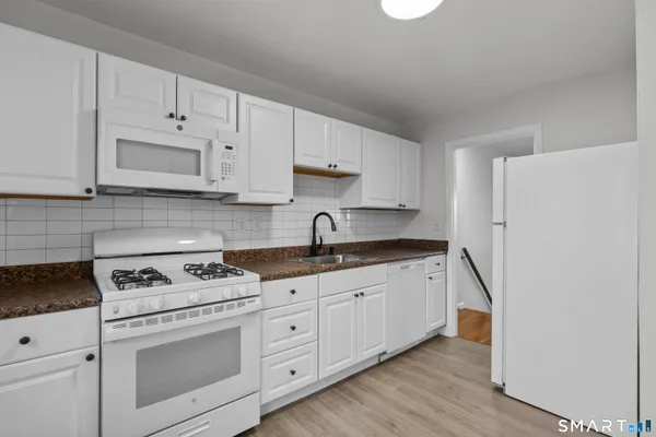 a kitchen with granite countertop white cabinets and white appliances