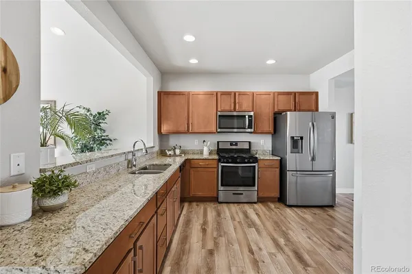 a kitchen with granite countertop a refrigerator stove and sink
