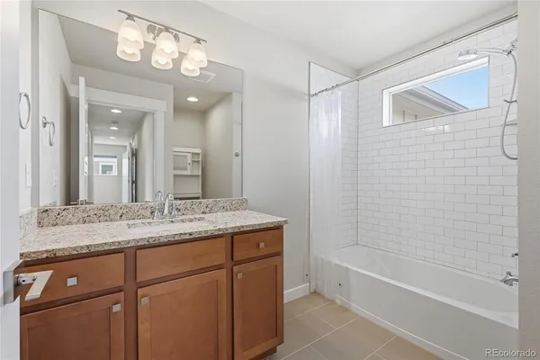 a bathroom with a granite countertop sink a toilet mirror and bathtub