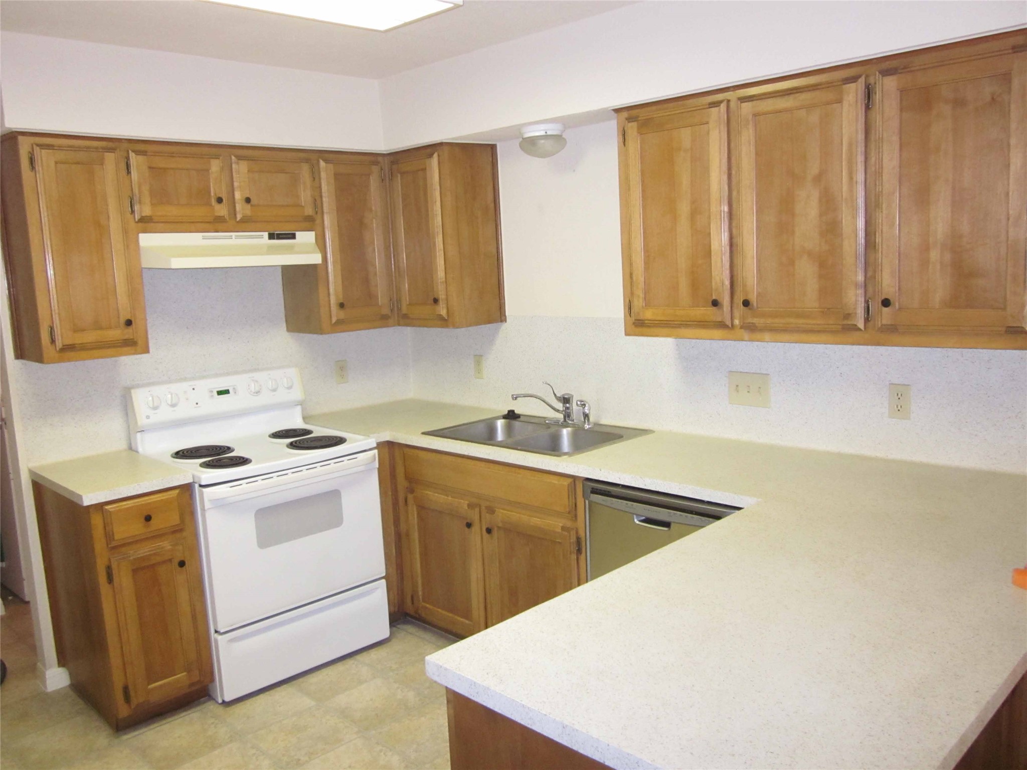 102 Verna Spur, Unit B Georgetown, TX 78628 - Photo 9 of 18 Kitchen featuring white range with electric cooktop, light countertops, wood finish cabinets, and stainless steel dishwasher