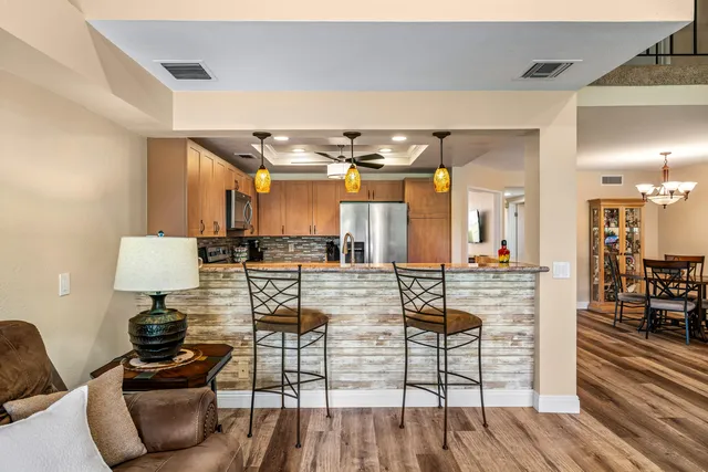 a kitchen with stainless steel appliances granite countertop a refrigerator a stove and a sink with wooden floor