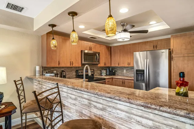 a kitchen with stainless steel appliances granite countertop a sink dishwasher a stove a dining table and chairs with wooden floor