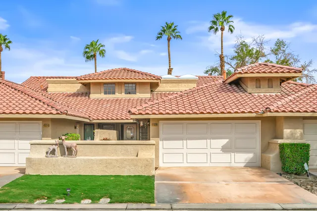 a front view of a house with a garden and plants