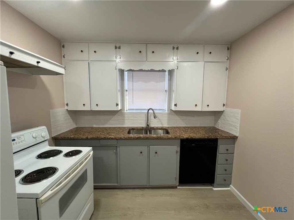 1009 Oak Street Refugio, TX 78377 - Photo 7 of 22 a kitchen with granite countertop a sink a stove and cabinets