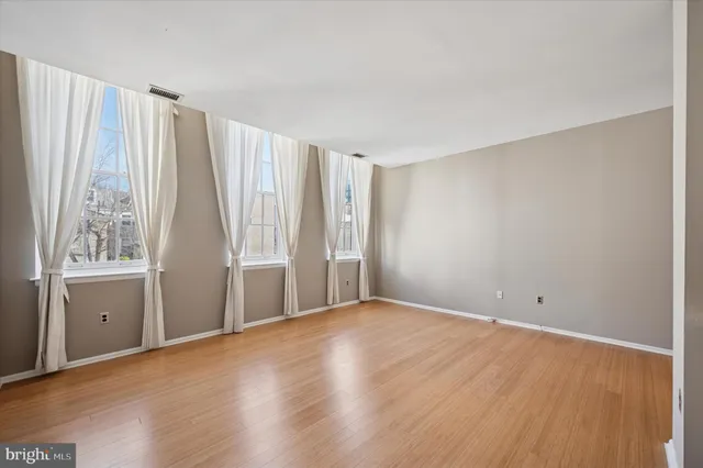 a view of an empty room with a window and wooden floor