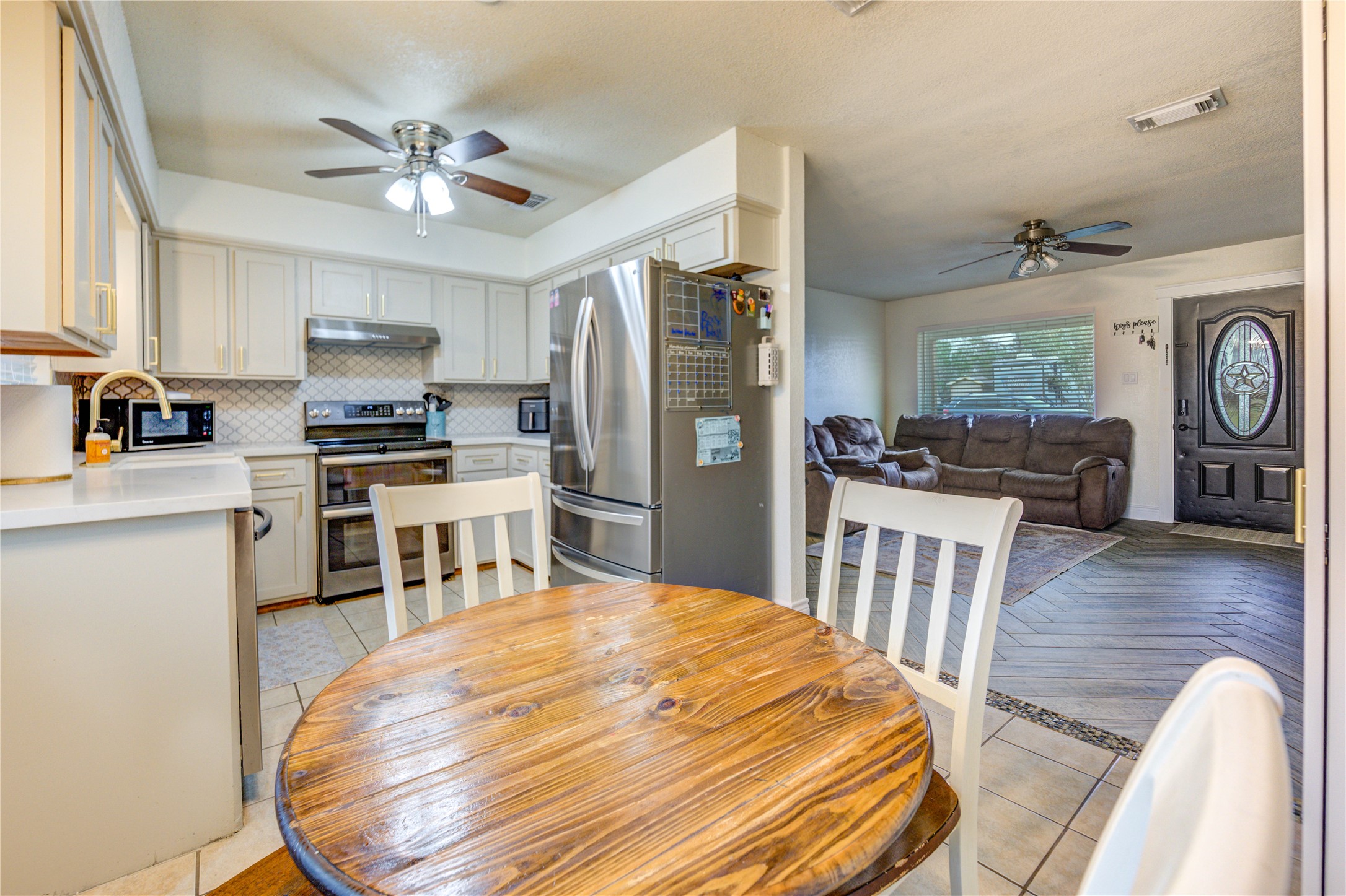 7706 Colston Place Santa Fe, TX 77510 - Photo 7 of 16 a kitchen with stainless steel appliances kitchen island granite countertop a refrigerator a stove top oven a sink dishwasher and white cabinets with wooden floor