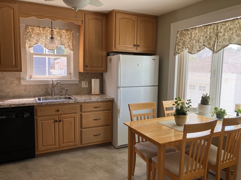 93 Crown Avenue Riverside, RI 02915 - Photo 11 of 33 a kitchen with a refrigerator a stove a sink dishwasher with a dining table and chairs