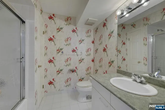 a bathroom with a granite countertop sink a toilet and shower curtain
