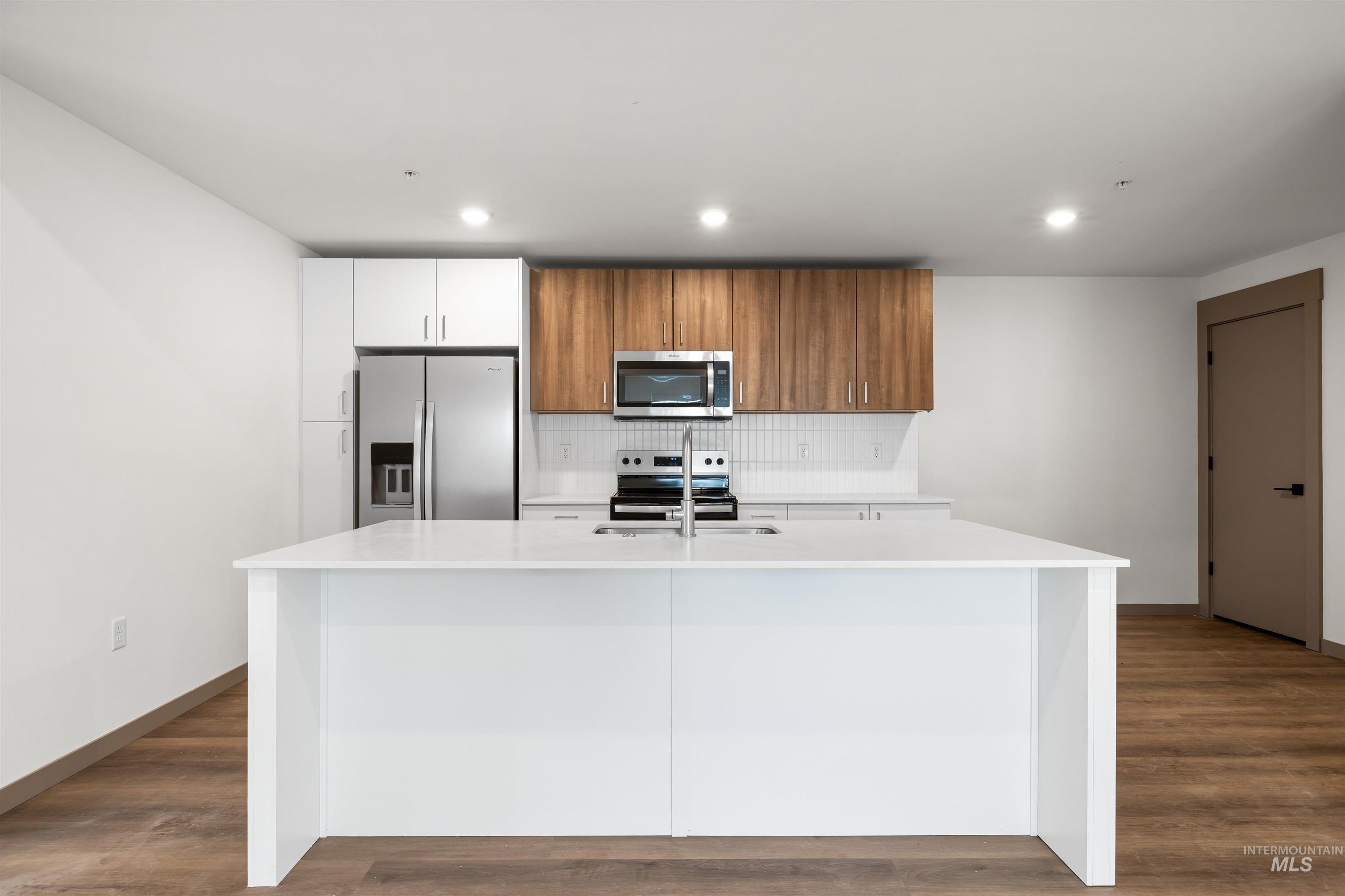 2010 Wimbledon Court Hailey, ID 83333 - Photo 20 of 46 Kitchen featuring brown cabinets, tasteful backsplash, stainless steel appliances, a kitchen island with sink, and white cabinets