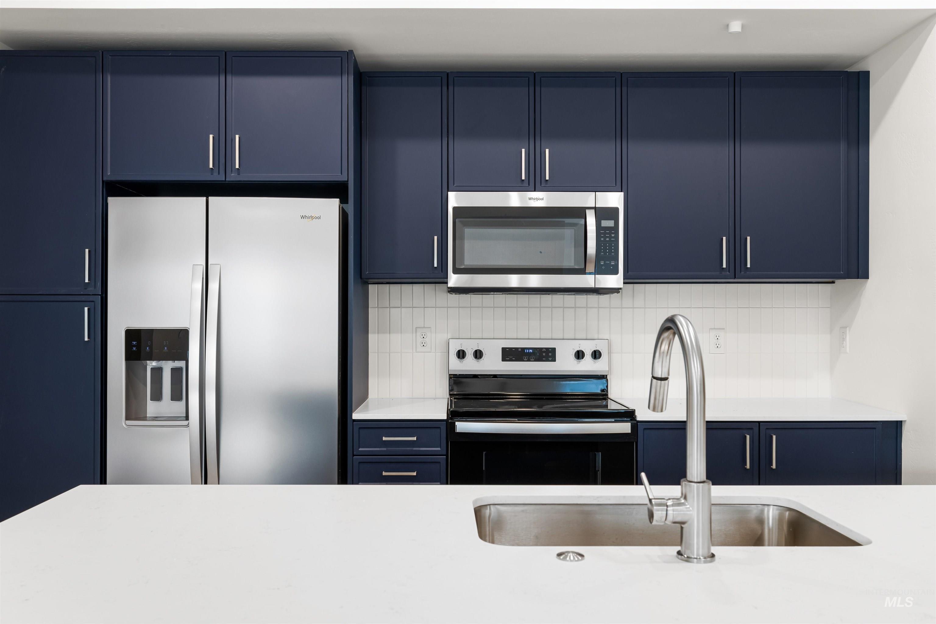 2010 Wimbledon Court Hailey, ID 83333 - Photo 6 of 46 Kitchen with blue cabinets, stainless steel appliances, tasteful backsplash, and light stone countertops