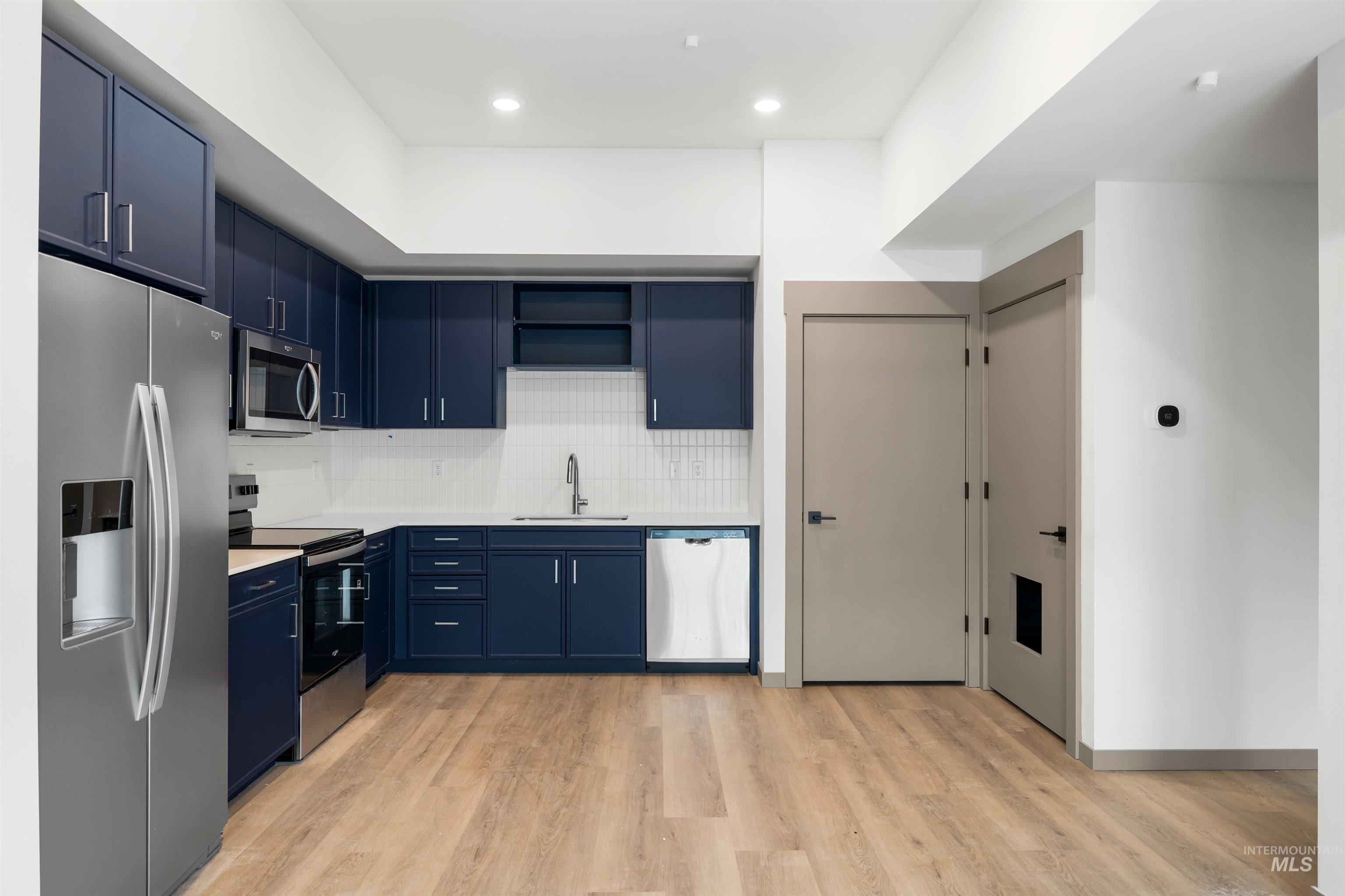 2010 Wimbledon Court Hailey, ID 83333 - Photo 7 of 46 Kitchen featuring blue cabinets, stainless steel appliances, tasteful backsplash, light wood finished floors, and open shelves