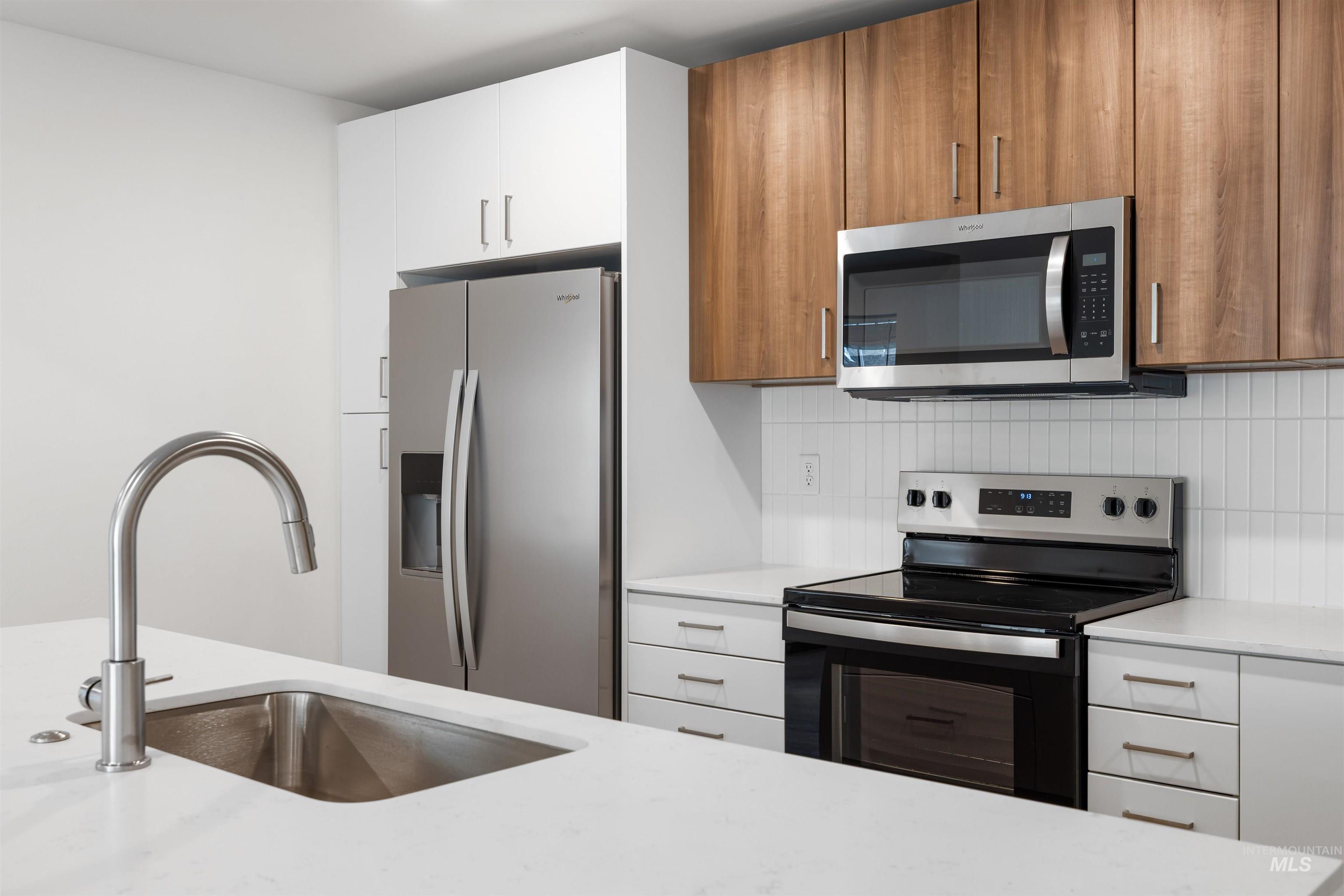 2010 Wimbledon Court Hailey, ID 83333 - Photo 10 of 46 Kitchen with stainless steel appliances, backsplash, light stone counters, brown cabinetry, and modern cabinets