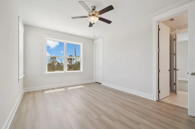 a view of an empty room with window and wooden floor