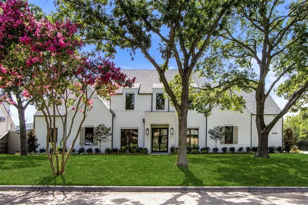 a view of a white house with a big yard and large trees