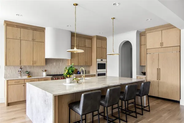 a kitchen with stainless steel appliances granite countertop a dining table chairs sink and cabinets