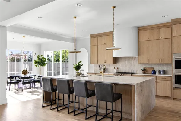 a kitchen with stainless steel appliances granite countertop a stove top oven a sink a dining table and chairs with wooden floor