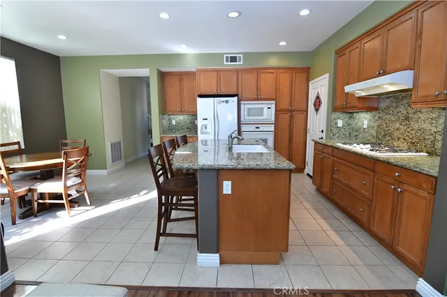 a dining hall with stainless steel appliances granite countertop a table chairs and a refrigerator