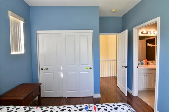 a view of a hallway with wooden floor and a bathroom
