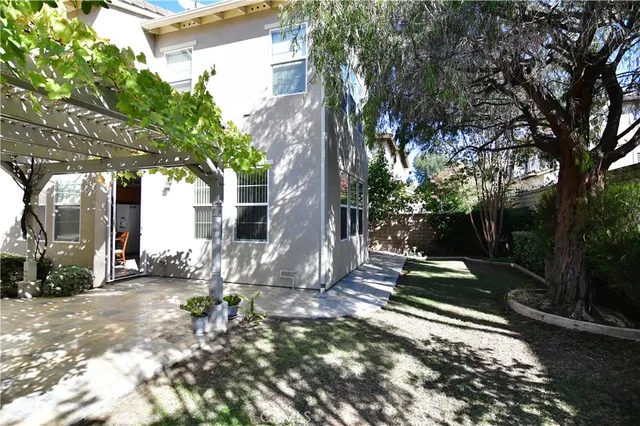 a backyard of a house with table and chairs under an umbrella
