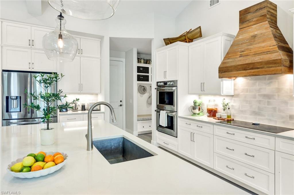 3700 11th Avenue Southwest Naples, FL 34117 - Photo 11 of 50 a kitchen with a sink dishwasher a dining table and chairs with white cabinets