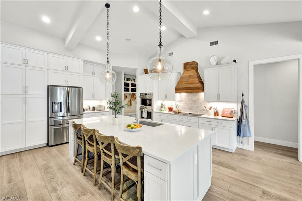 3700 11th Avenue Southwest Naples, FL 34117 - Photo 10 of 50 a kitchen with stainless steel appliances kitchen island granite countertop a table chairs and a refrigerator
