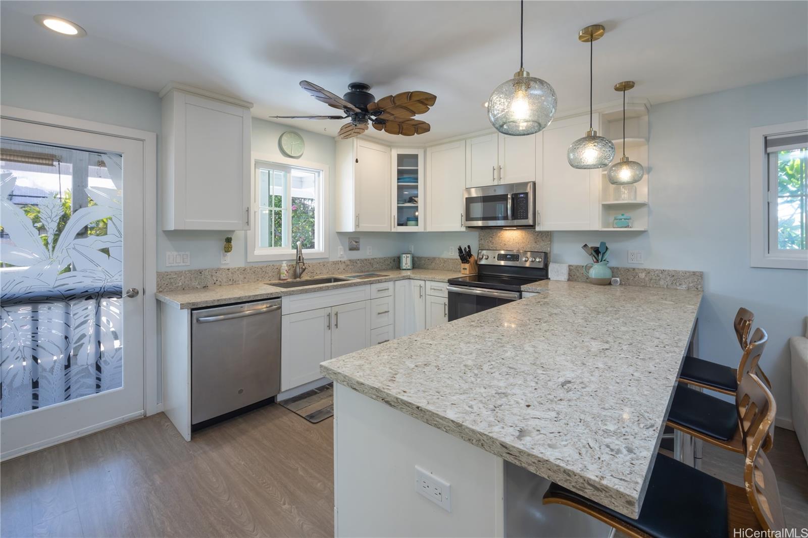 409 Wanaao Road Kailua, HI 96734 - Photo 18 of 25 a kitchen with a sink dishwasher a stove a microwave oven with a dining table and chairs