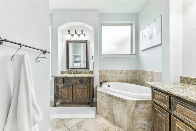a bathroom with a granite countertop sink a mirror and a bathtub