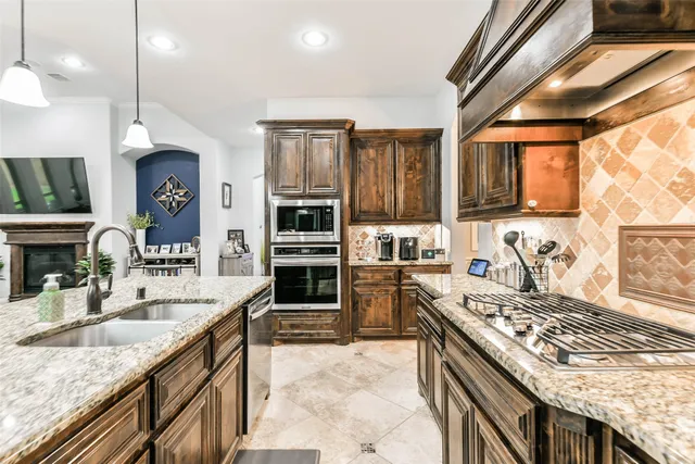 a kitchen with stainless steel appliances granite countertop a stove a sink and a microwave