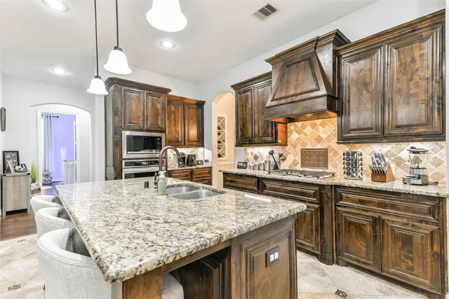 a kitchen with granite countertop a sink a stove top oven a counter space and cabinets