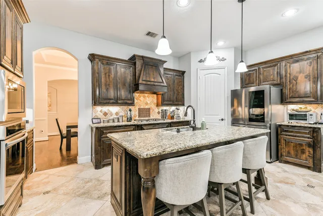 a kitchen with stainless steel appliances granite countertop a kitchen island hardwood floor sink stove dining table and chairs