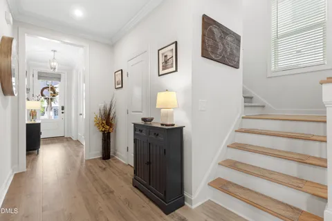 a view of a hallway with wooden floor staircase and a living room