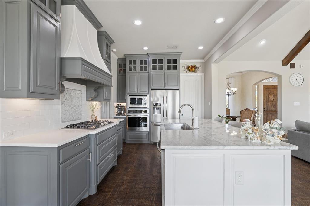 542 Pierce Road Red Oak, TX 75154 - Photo 12 of 27 Gourmet kitchen featuring grey shaker-style cabinetry, stainless steel appliances, a gas cooktop, and an expansive kitchen island with a built-in sink