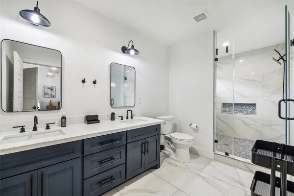 a bathroom with a double vanity sink toilet mirror and shower