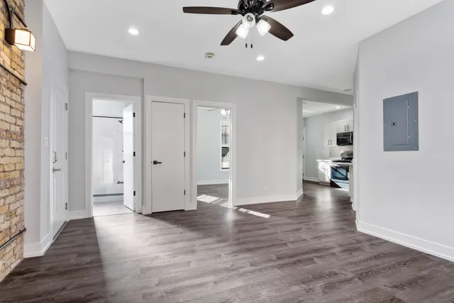 a view of an empty room and kitchen with wooden floor