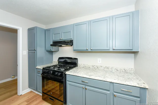 a kitchen with granite countertop white cabinets and a stove top oven