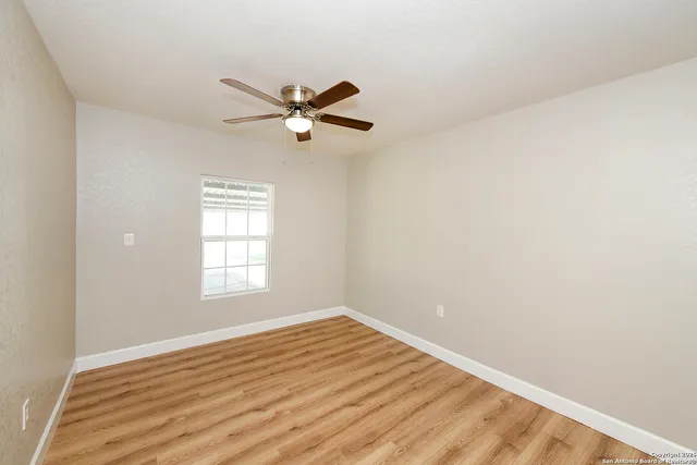 a view of empty room with wooden floor and fan