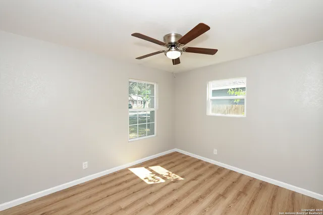 a view of a big room with wooden floor and windows