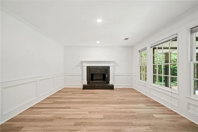 a view of an empty room with wooden floor fireplace and a window