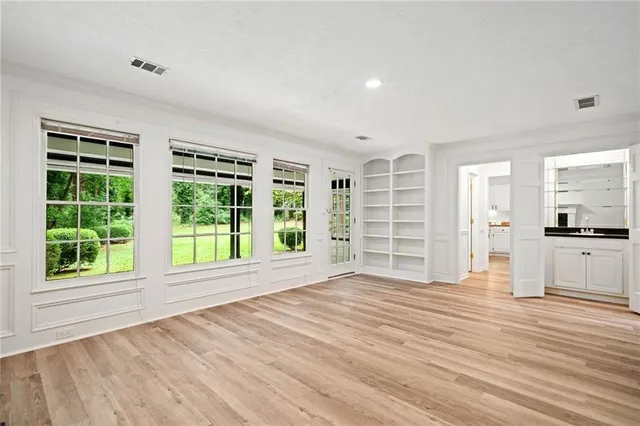 a view of an empty room with a window and wooden floor