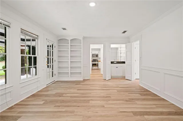 a view of an empty room with a window and wooden floor