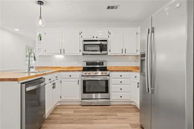 a kitchen with granite countertop a sink stainless steel appliances and white cabinets