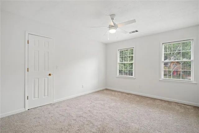 an empty room with windows and fan