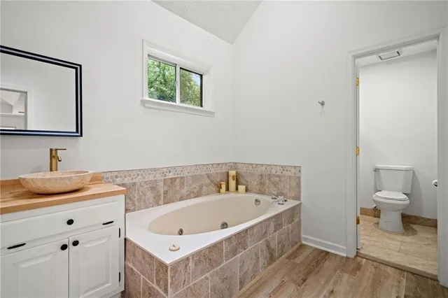 a bathroom with a tub sink toilet and mirror